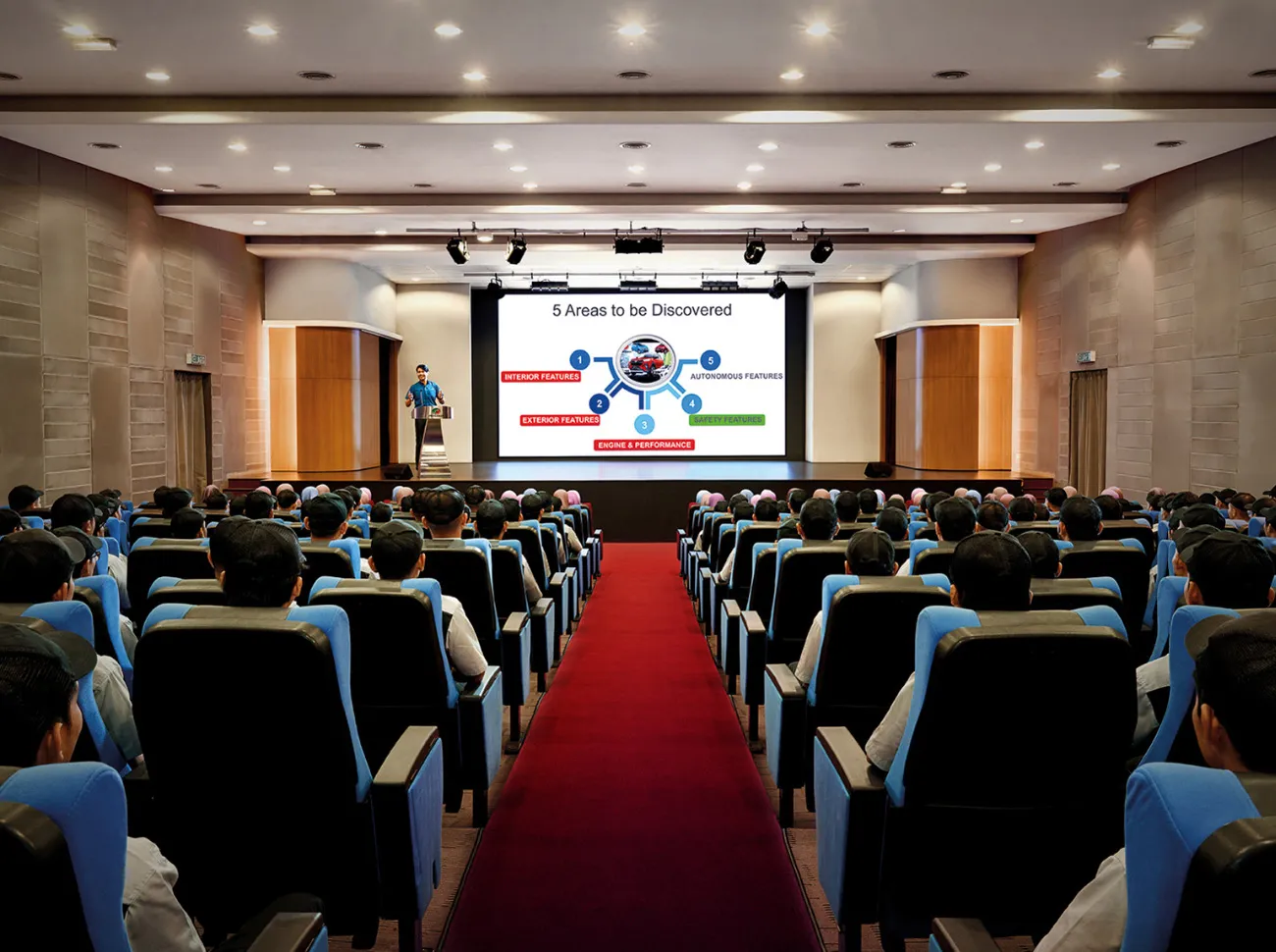 Perodua car under warm festival bulbs at dusk, gentle points of light adding depth.